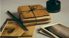 photo of old books wrapped in brown paper with an ink pen an old photograph.